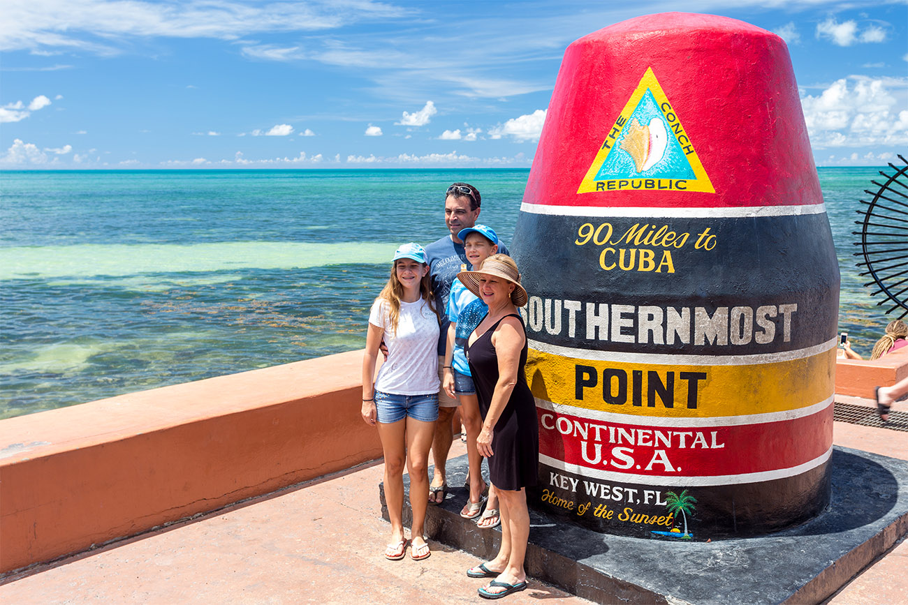A family poses for a photograph at the Southernmost Point marker in Key West, Fla., one of the most photographed icons in the Florida Keys.  The concrete buoy, which commemorates the southernmost spot of land in the continental United States, is painted with letters proclaiming that it stands 90 miles from Cuba and more than 150 miles from Miami. FOR EDITORIAL USE ONLY. Photo by Laurence Norah/Florida Keys News Bureau