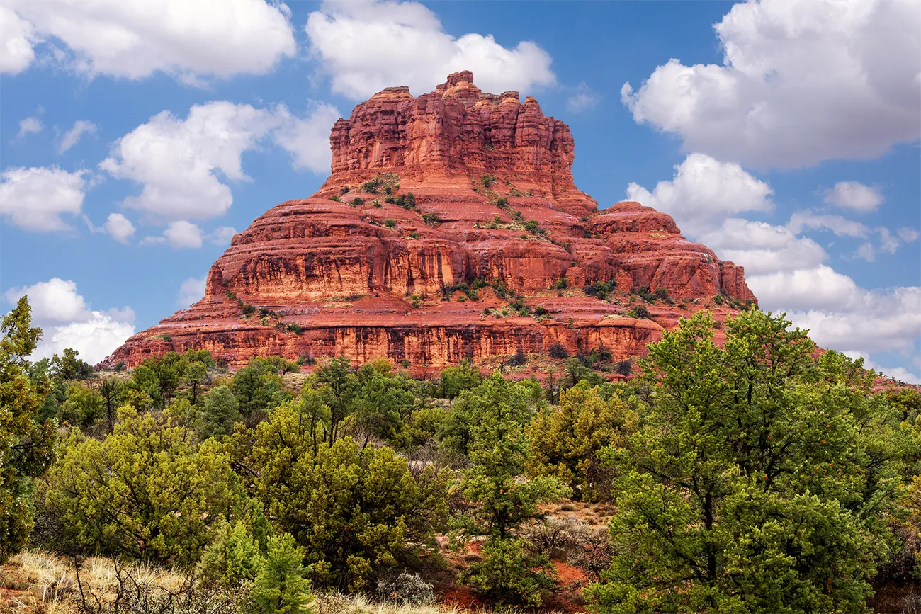 A scenic view of a red rock formation with rounded peaks in the desert