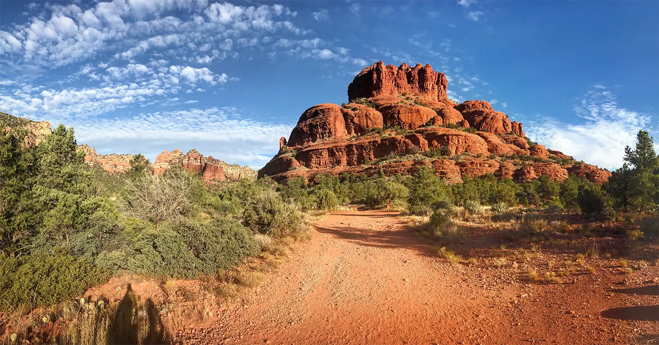 A scenic view of a red rock formation with rounded peaks in the desert