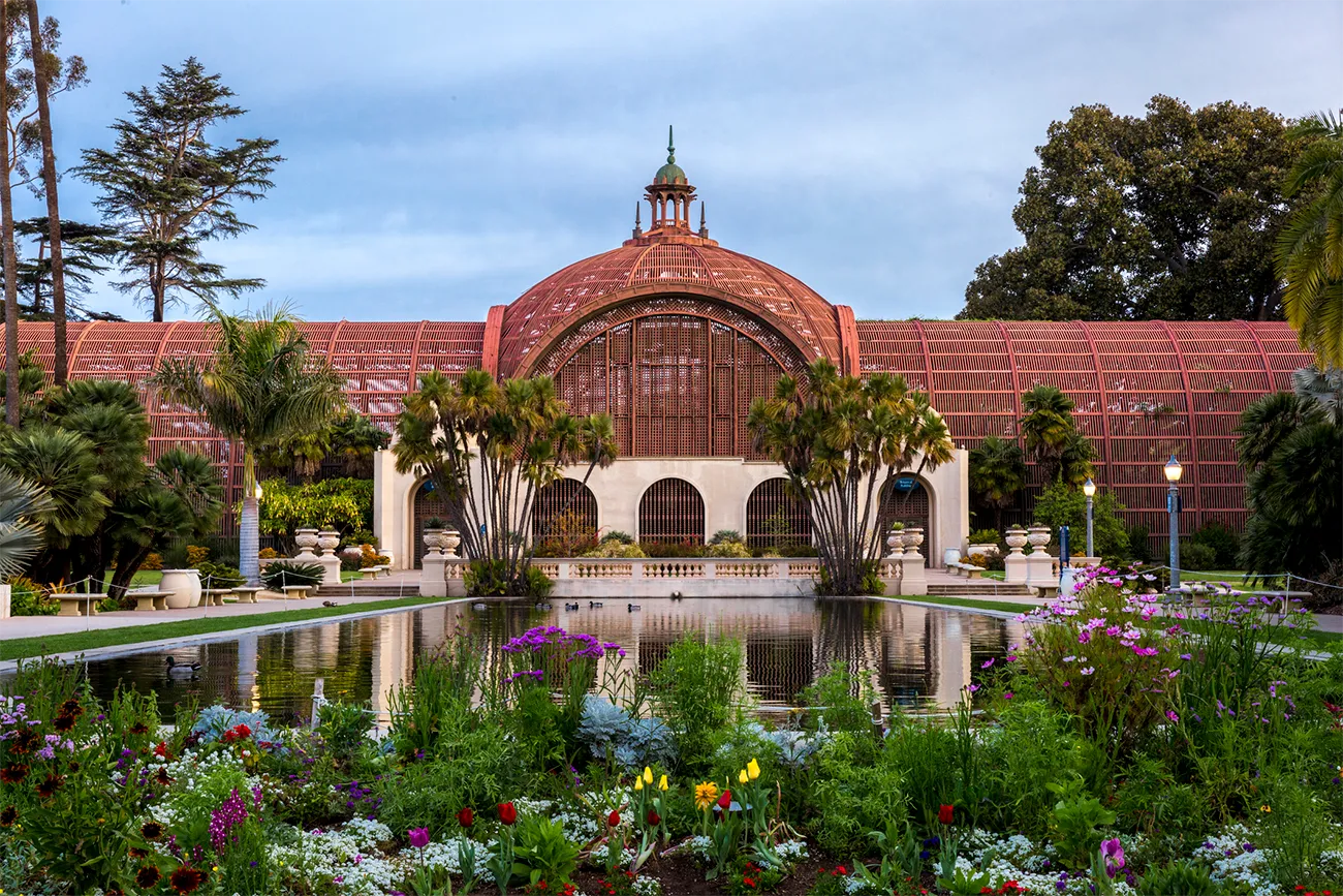 Balboa Park arboretum in the early morning light reflected in the water with flowers and trees.
