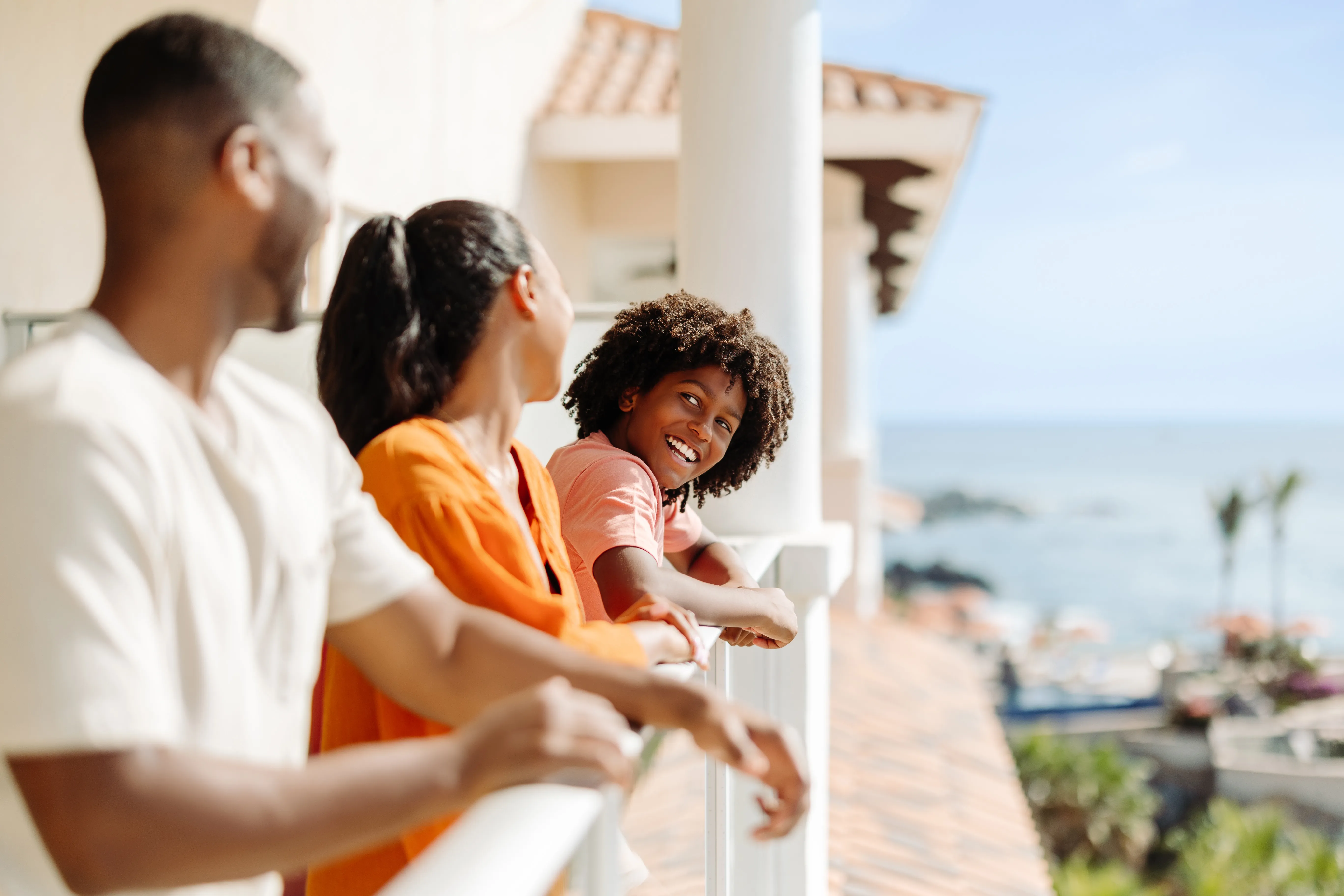 Family of four sitting on a balcony overlooking a scenic landscape.