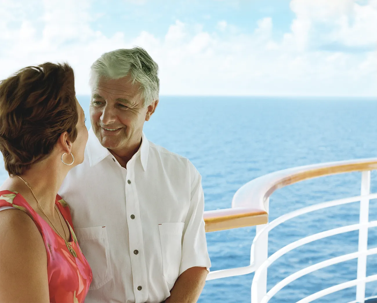 Two people standing on the deck of a ship or a boat with a view of the ocean and part of the ship's railing.