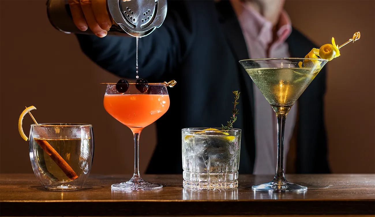 Four cocktails, garnished with citrus slices or peels, highlighting the art of cocktail preparation