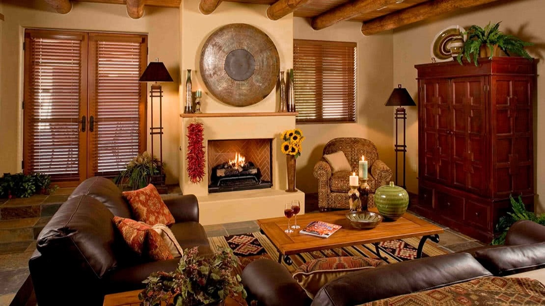 A cozy living room with shuttered windows, leather couches, and a fireplace