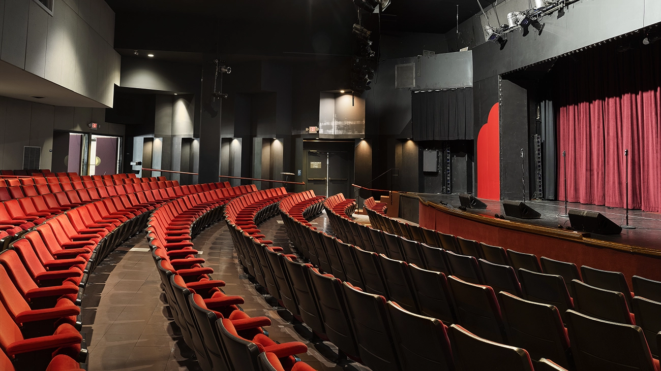 Interior of a theater at The Welk resort with empty red seats and a stage.
