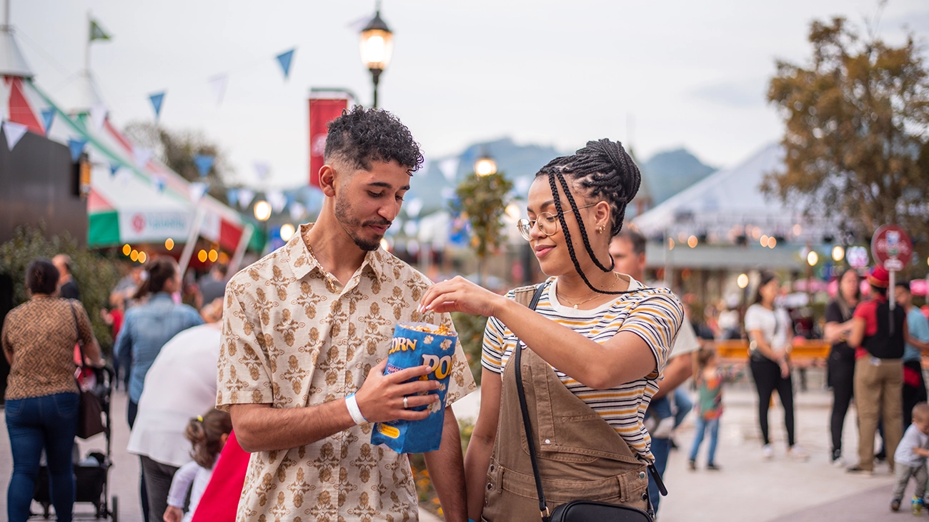 Happy couple sharing popcorn at an outdoor festival