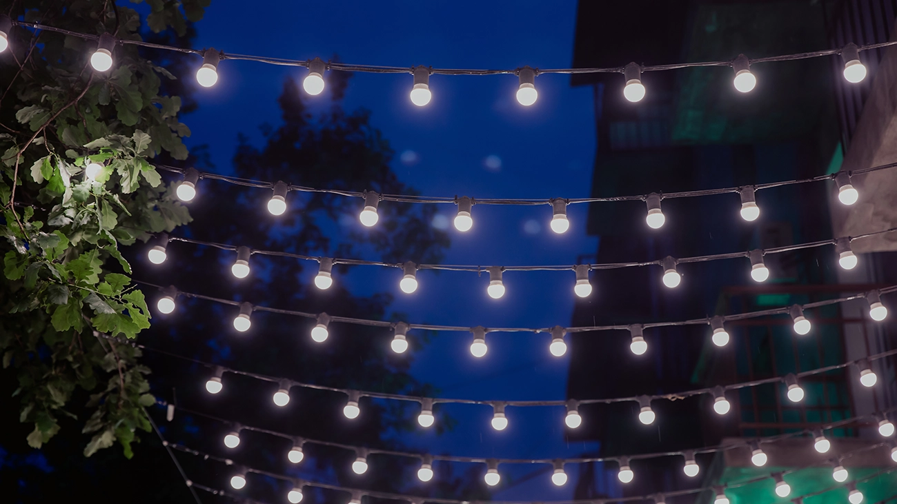Rows of attractive overhead string lights illuminating a courtyard at night