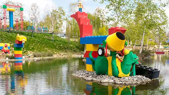 Colorful Lego sculpture of a dragon on a small island in a lake